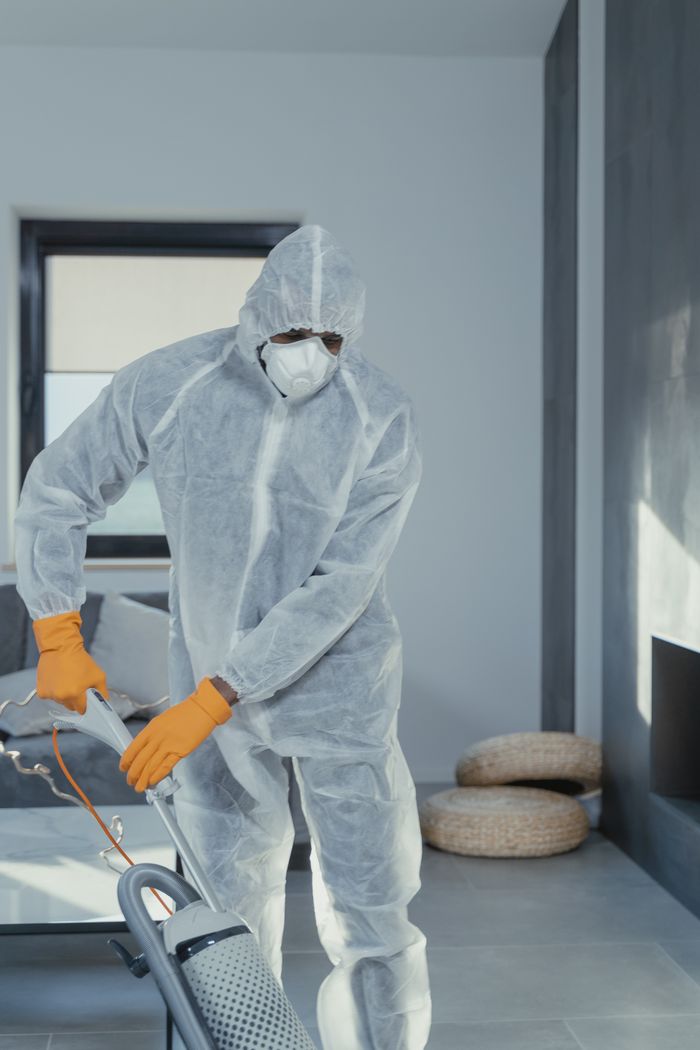 home-img A person in personal protective equipment vacuuming indoors, ensuring a thorough clean.